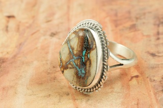 Genuine Boulder Turquoise set in Sterling Silver Ring. The cabachon is Boulder Turquoise, you can see the veins of Turquoise running through the host rock. The Boulder Turquoise Mine is located in northeast Nevada. It was discovered in 1970 by a Shoshone sheep herder. Production is small due to the remote location and winter weather. Boulder Turquoise is valued for both it's beauty and rarity. Every stone is unique. Created by Navajo Artist Larson Lee. Signed by the artist.